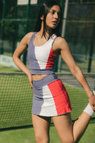 Mujer estirando con conjunto de padel azul y rojo - Plano medio